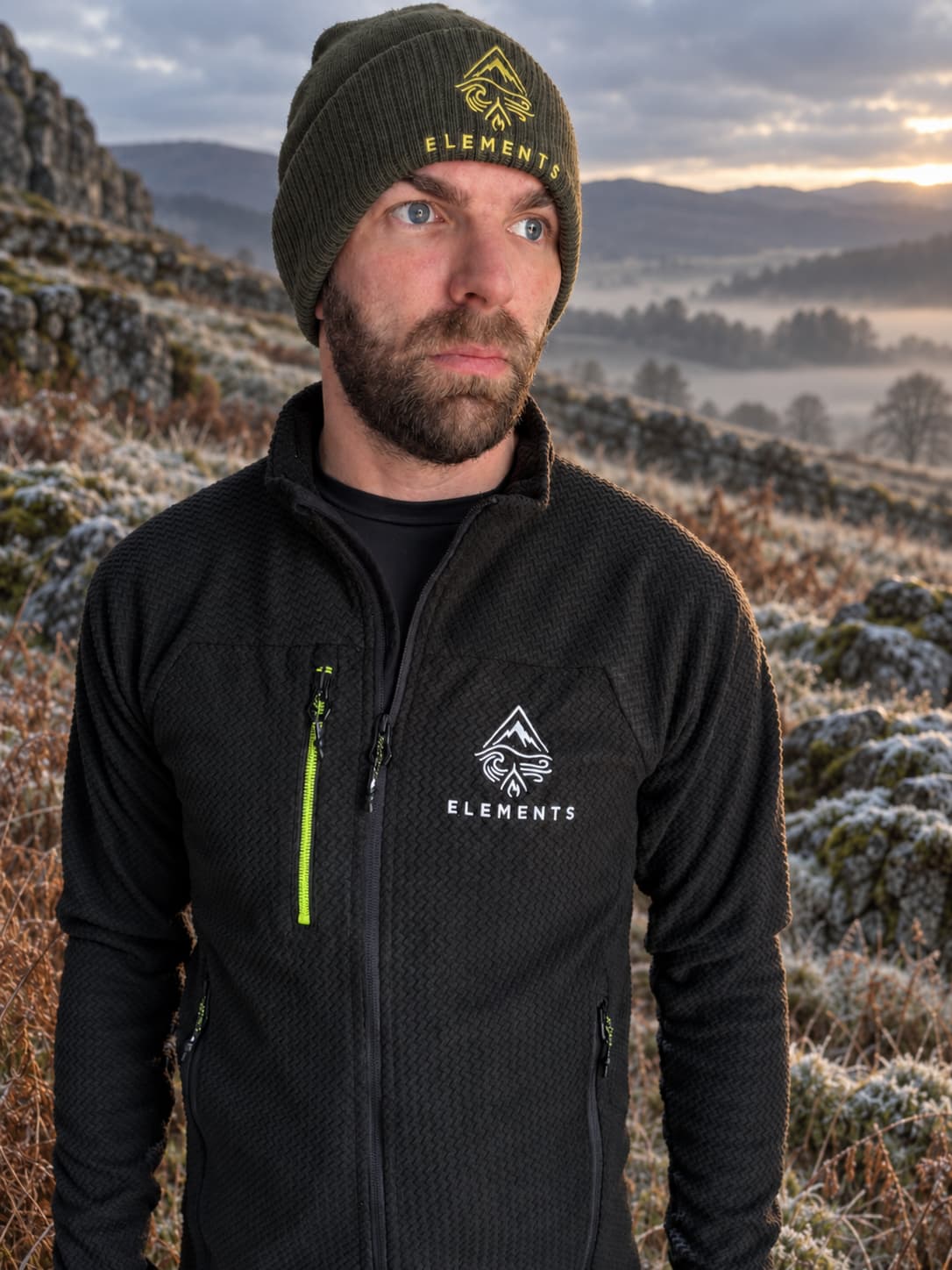 Conor wearing the Elements beanie and fleece above a frosted valley at sunrise